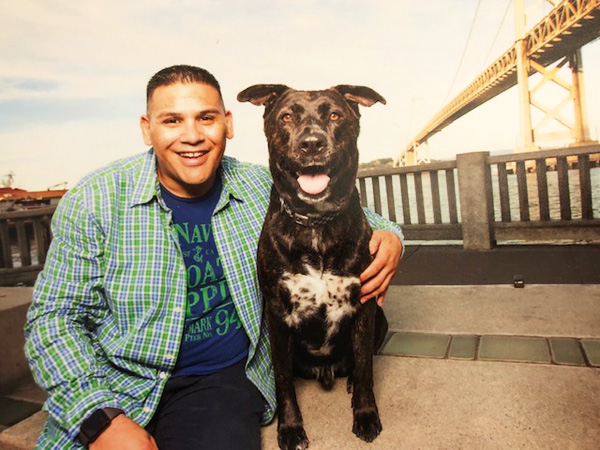 Man sitting next to black and white dog.